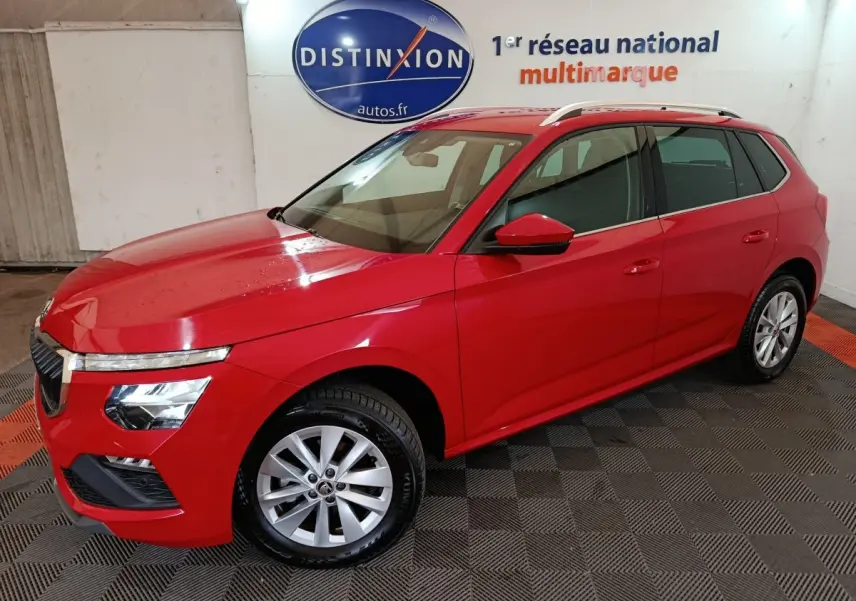 Vue 3/4 avant gauche d'un Skoda Kamiq rouge 2024 avec jantes alliage et barres de toit argentées.