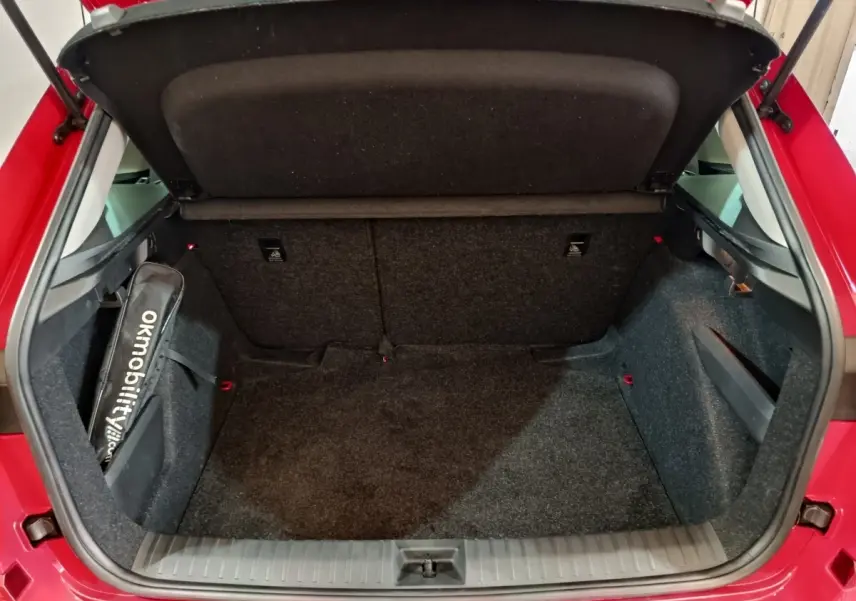 Coffre ouvert vu de l'arrière d'un Skoda Kamiq rouge 2024, espace de chargement propre et bien aménagé.