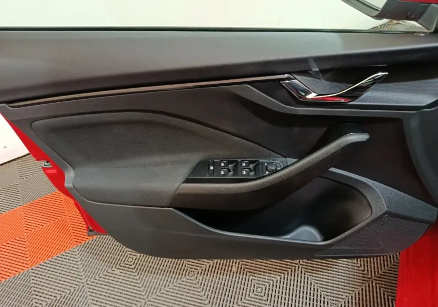 Vue rapprochée de la porte avant gauche noire avec commandes électriques sur une Skoda Kamiq rouge 2024.