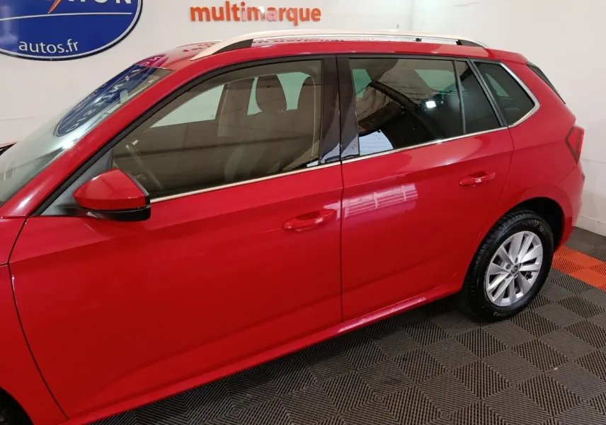 Vue latérale droite d'un Skoda Kamiq rouge 2024 avec rétroviseurs rouges et rails de toit argentés visibles.