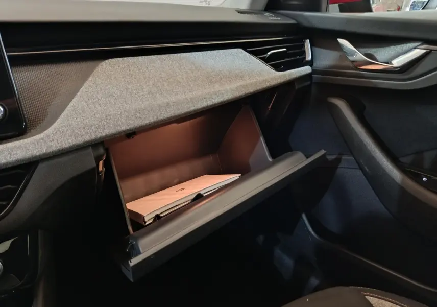 Intérieur SKODA KAMIQ 2024, vue sur la boîte à gants ouverte côté passager avec tableau de bord gris et noir.