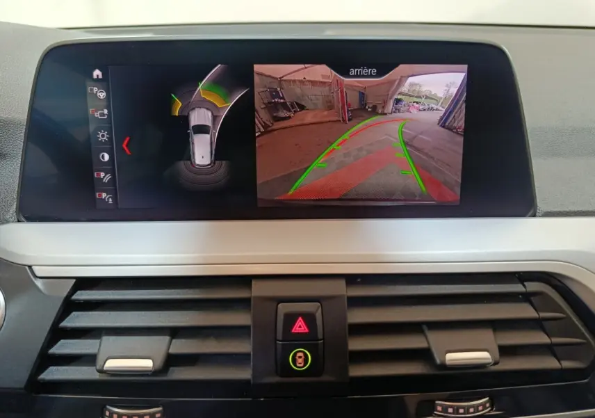 Écran central du BMW X3 xDrive30e 2020 montrant la caméra de recul et l’aide au stationnement en intérieur.