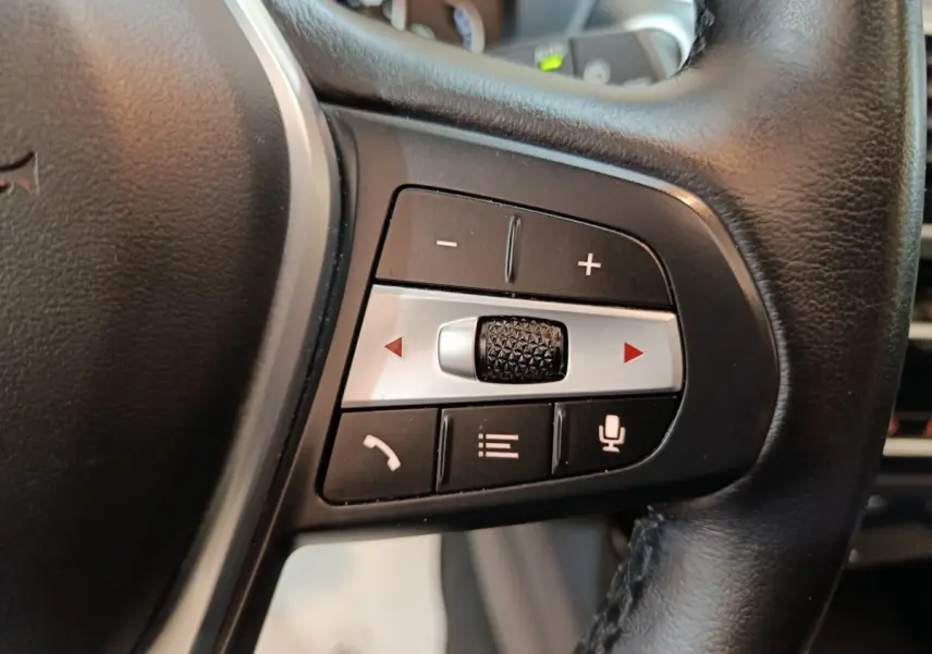 Gros plan sur les commandes multifonctions en cuir noir du volant BMW X3 xDrive30e 2020, boutons de volume et appel.