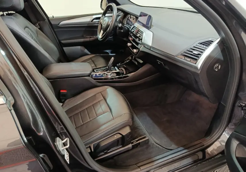 Intérieur avant droit BMW X3 xDrive30e 2020, sièges cuir noirs, tableau de bord moderne avec écran central et volant multifonctions.