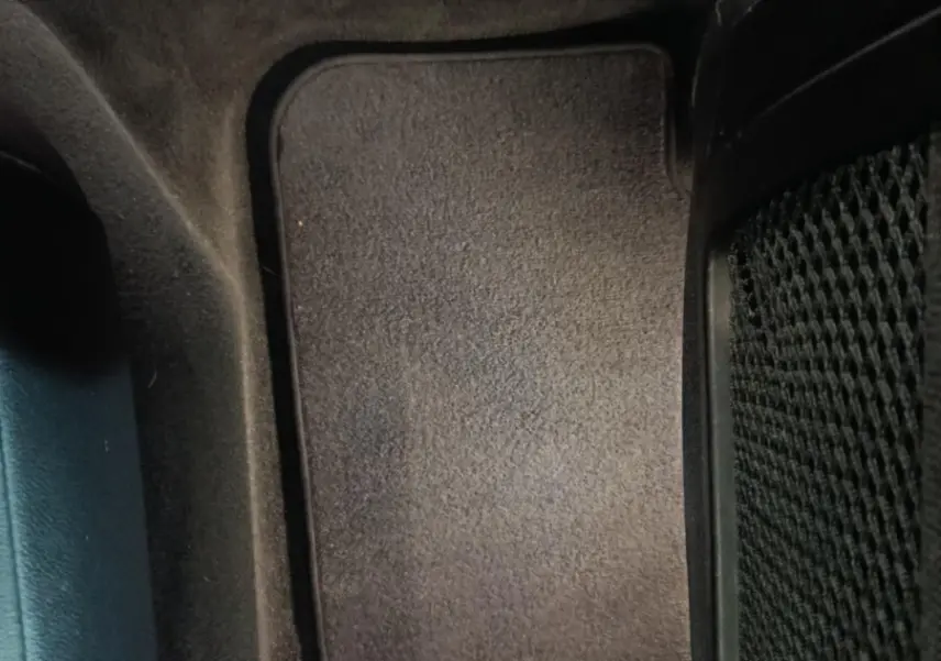 Vue rapprochée du tapis de sol noir côté arrière droit intérieur d’un BMW X3 xDrive30e gris foncé.