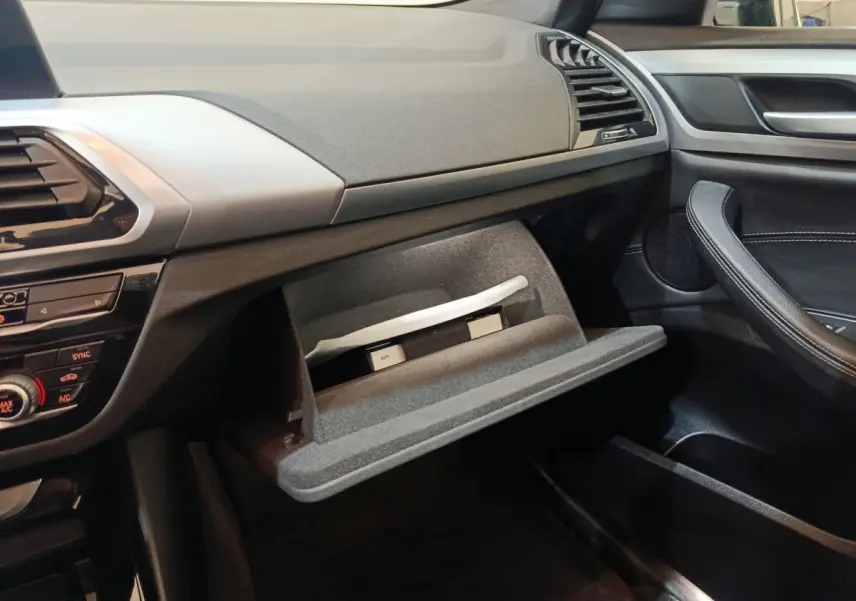Intérieur côté passager d’un BMW X3 xDrive30e 2020 gris foncé, boîte à gants ouverte avec documents visibles.