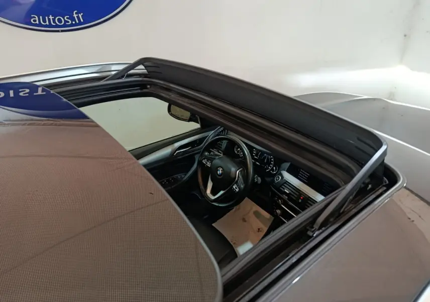 Vue plongeante sur l'intérieur gris foncé d'une BMW X3 xDrive30e 2020 avec toit ouvrant panoramique ouvert.