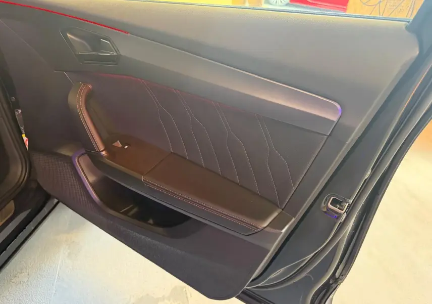 Vue rapprochée de la porte avant gauche noire du CUPRA Formentor 2025 avec surpiqûres orange et poignée intégrée.