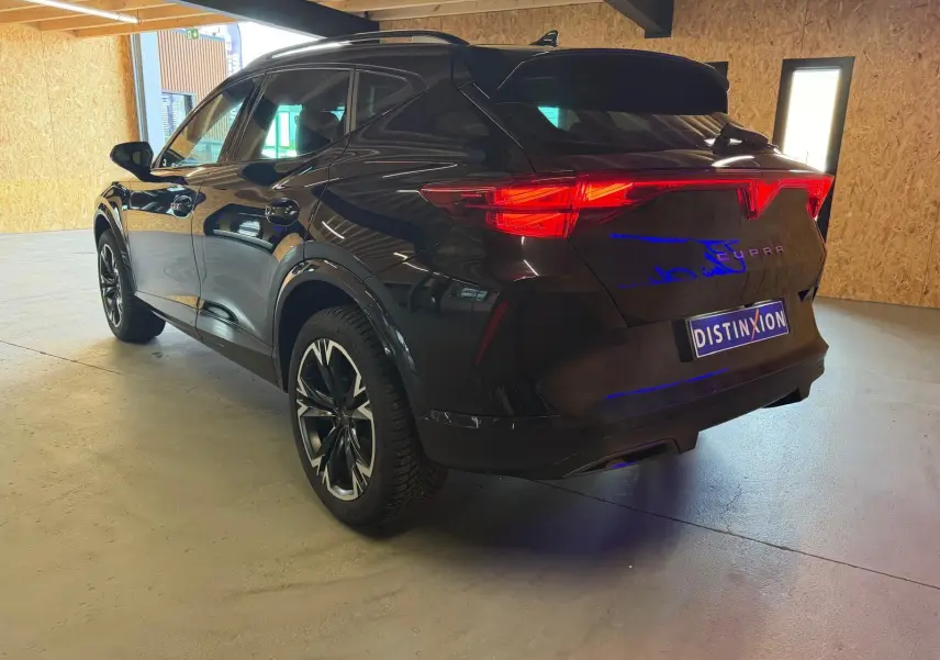 Vue 3/4 arrière droite du CUPRA Formentor noir 2025 avec jantes alliage et feux arrière LED allumés.