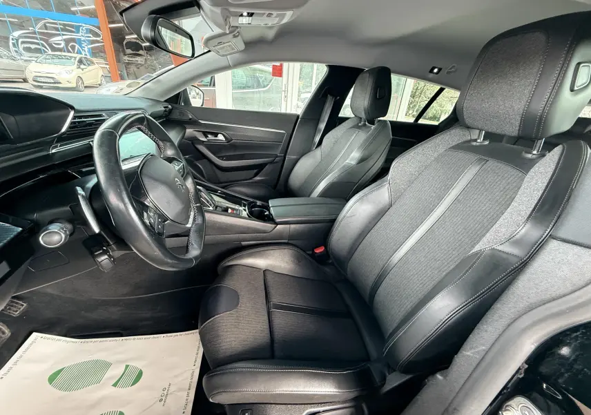 Intérieur noir de la Peugeot 308 SW vu côté conducteur, sièges tissu et cuir avec volant multifonctions.