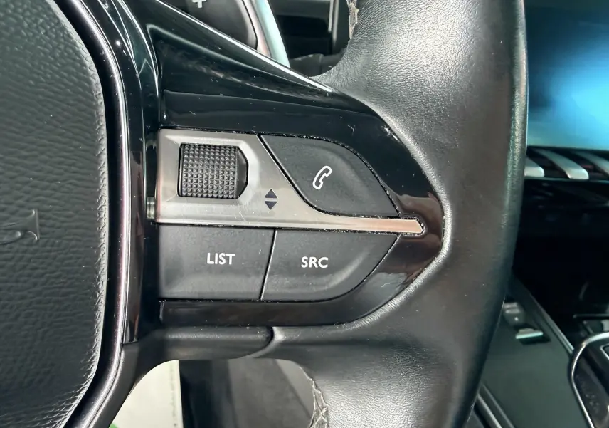 Gros plan sur les commandes gauche du volant noir de la Peugeot 308 SW 2018, avec boutons de téléphone et liste.