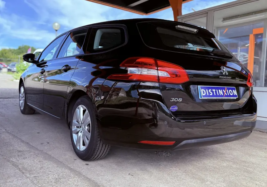 Peugeot 308 SW noire métal vue 3/4 arrière droit, mettant en valeur ses feux arrière et sa silhouette élégante.