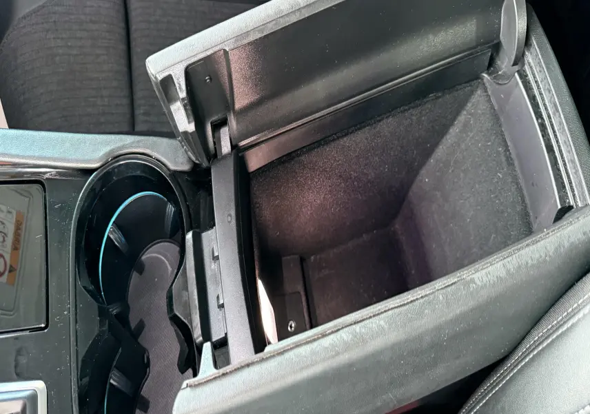 Vue rapprochée de la console centrale ouverte avec rangement et porte-gobelets dans une Peugeot 308 SW noir métal.