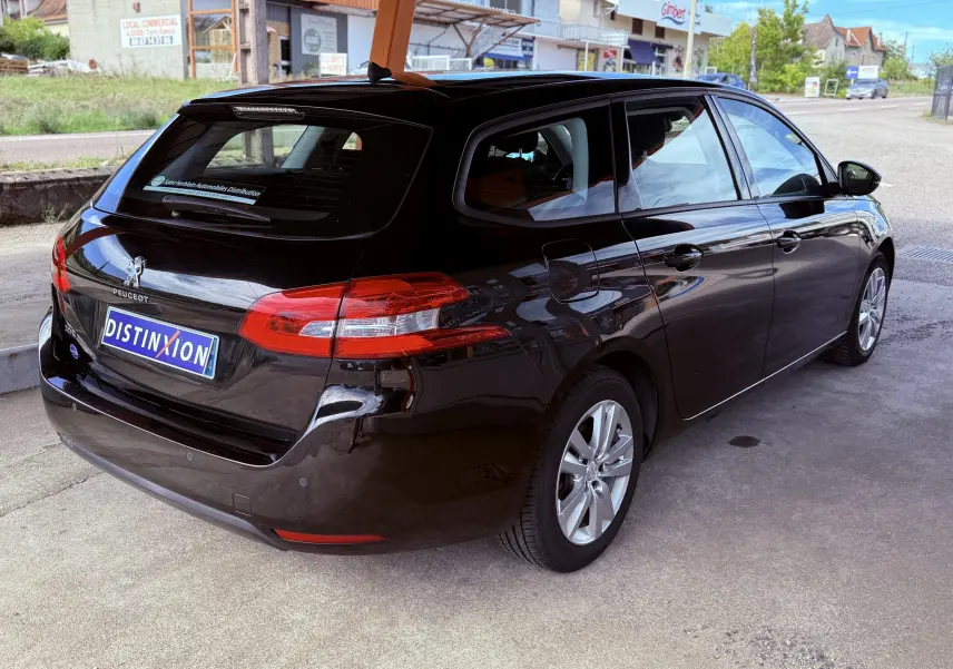 Peugeot 308 SW noir métal vue 3/4 arrière côté droit, avec feux arrière allongés et jantes alliage 16 pouces.