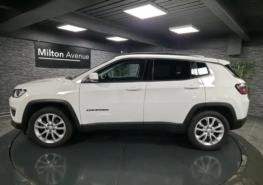 Jeep Compass blanc en profil côté gauche, avec jantes alliage 18 pouces et vitres arrière surteintées.