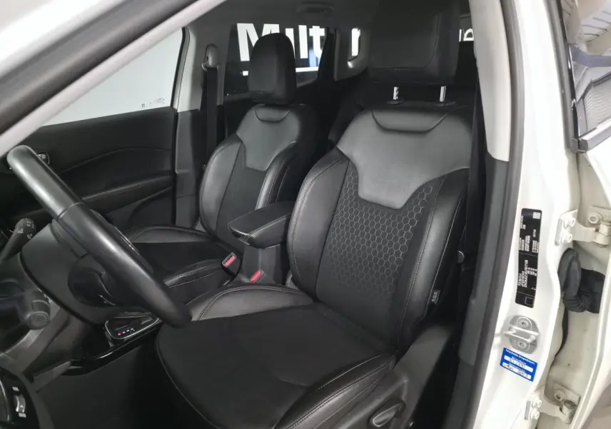Intérieur avant du Jeep Compass blanc 2020, sièges simili cuir noirs avec motifs hexagonaux, volant visible côté gauche.