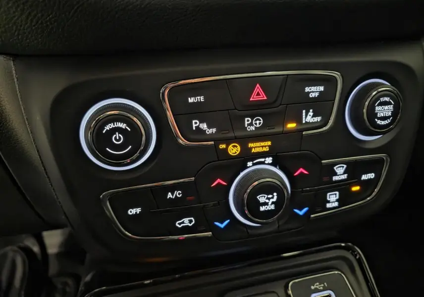 Panneau de commande central noir avec boutons lumineux de climatisation et audio dans un Jeep Compass blanc de 2020.