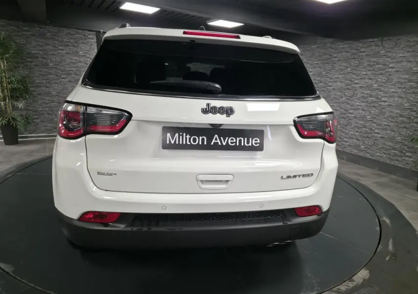 Vue arrière d'un Jeep Compass blanc Limited 2020 avec vitres arrière surteintées et logo distinctif sur le hayon.