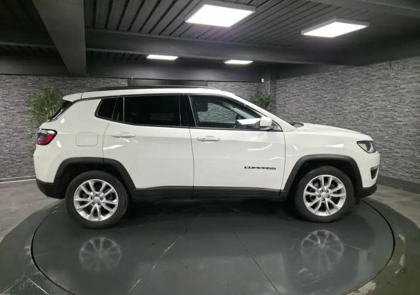 Jeep Compass blanc vu de profil côté gauche avec jantes alliage 18 pouces et vitres surteintées dans un studio.