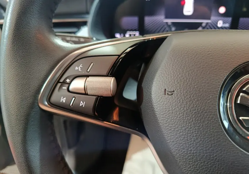 Gros plan sur le volant cuir noir du Skoda Kamiq 2024, avec commandes multifonctions et molette argentée.