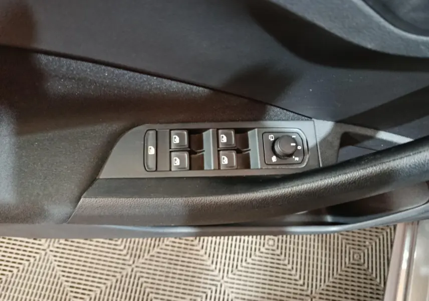 Gros plan sur les commandes de lève-vitres et réglage des rétroviseurs côté conducteur du Skoda Kamiq gris clair 2024.