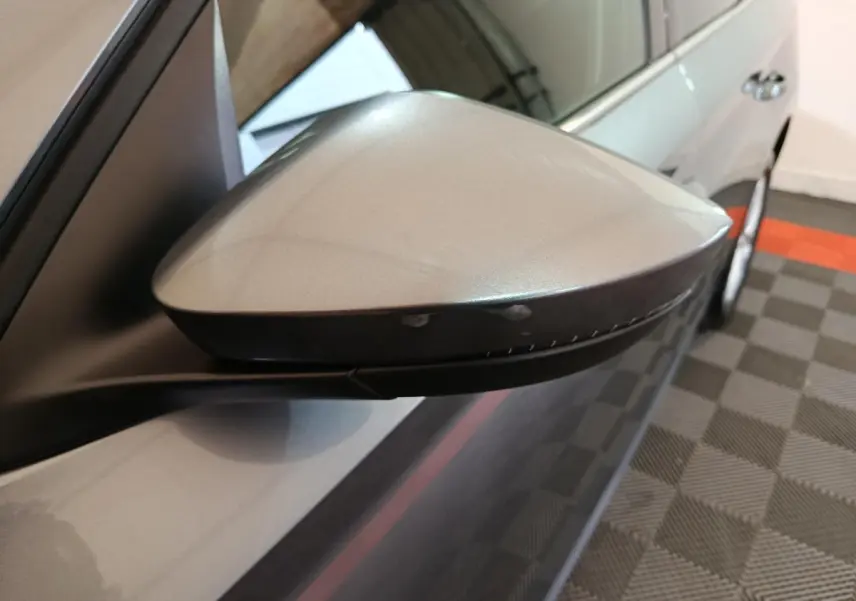 Gros plan sur le rétroviseur droit gris clair du Skoda Kamiq 2024, avec clignotant intégré et carrosserie visible.