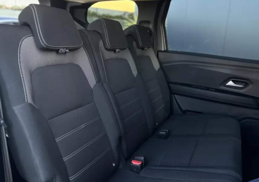 Vue latérale droite des sièges arrière noirs avec surpiqûres blanches du Dacia Jogger 2025, version Expression.