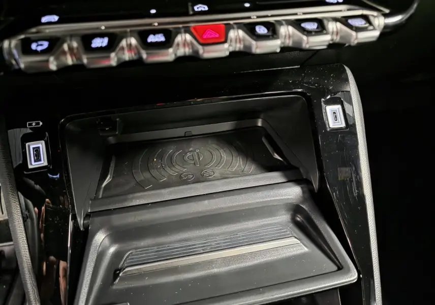 Détail de la console centrale noire du Peugeot 2008 2025 avec plateau de recharge sans fil et ports USB type C.