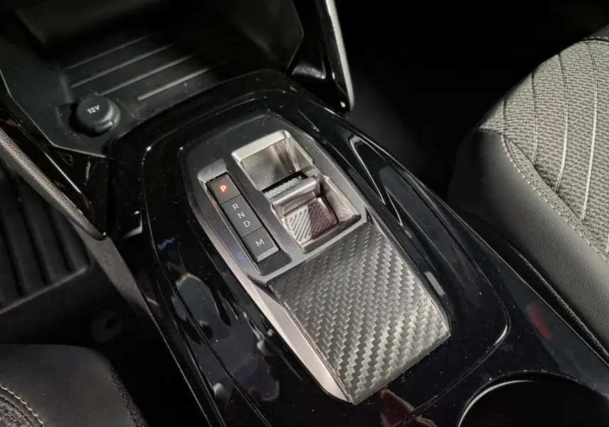 Vue rapprochée de la console centrale noire brillante avec sélecteur de boîte auto et tissu gris sur siège PEUGEOT 2008 2025.
