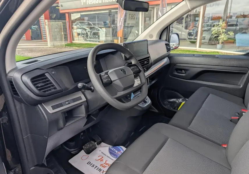 Intérieur avant du Peugeot Expert Fourgon noir 2025, vue côté conducteur avec tableau de bord et banquette passager grise.