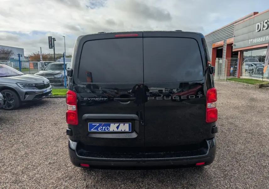 Vue arrière d'un Peugeot Expert Fourgon noir avec portes battantes et feux rouges visibles sur un parking.
