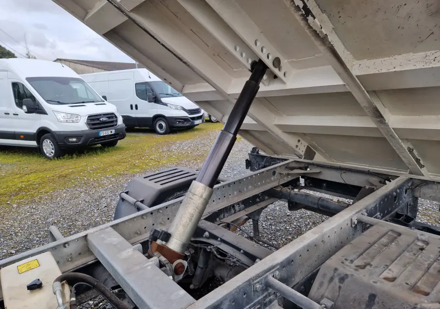 Vue rapprochée sous la benne relevée du camion blanc Iveco Daily 35C14 avec grue Palfinger et roues jumelées.