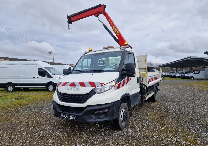 IVECO Daily Chassis Cabine blanc en 3/4 avant droit avec grue Palfinger rouge et benne arrière sur terrain gravillonné.