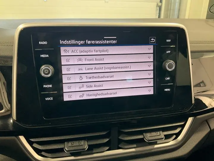 Écran tactile central du Volkswagen T-Roc 2025 affichant les réglages des aides à la conduite en intérieur noir.