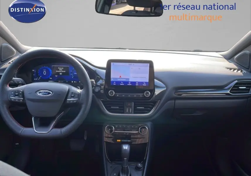 Vue intérieure frontale du tableau de bord noir d'une Ford Puma 2023 avec écran tactile et volant multifonction.