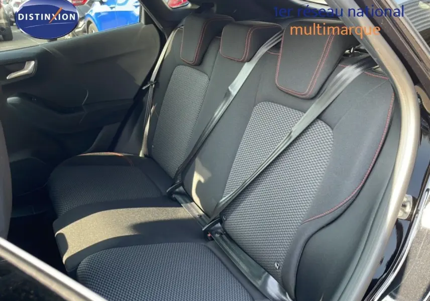 Vue intérieure côté arrière droit du Ford Puma noir agate métal, mettant en valeur les sièges arrière en tissu noir avec surpiqûres rouges.