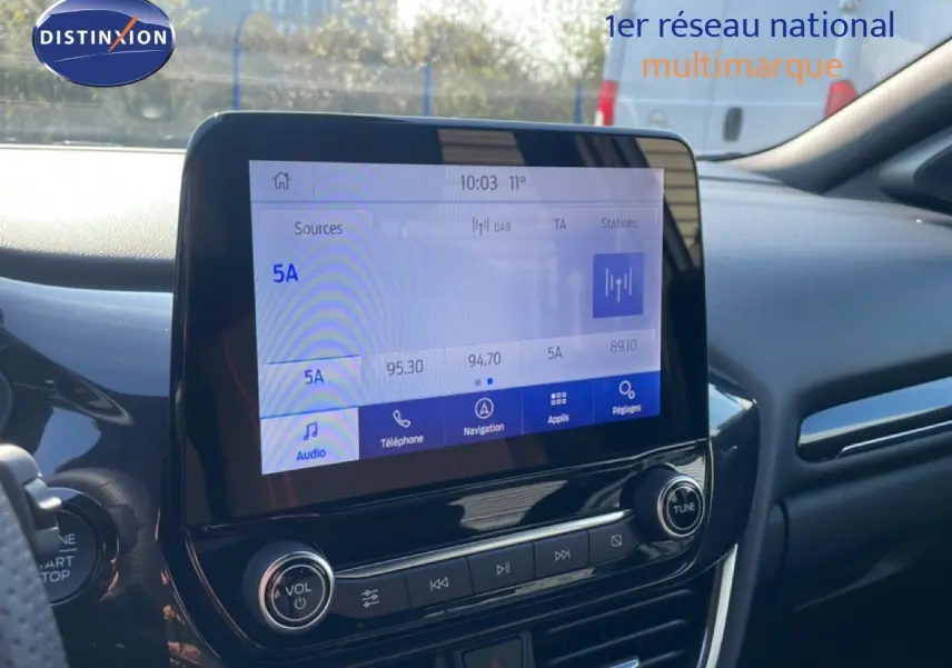 Vue intérieure du tableau de bord du Ford Puma 2023 noir agate, avec écran tactile central et commandes audio visibles.