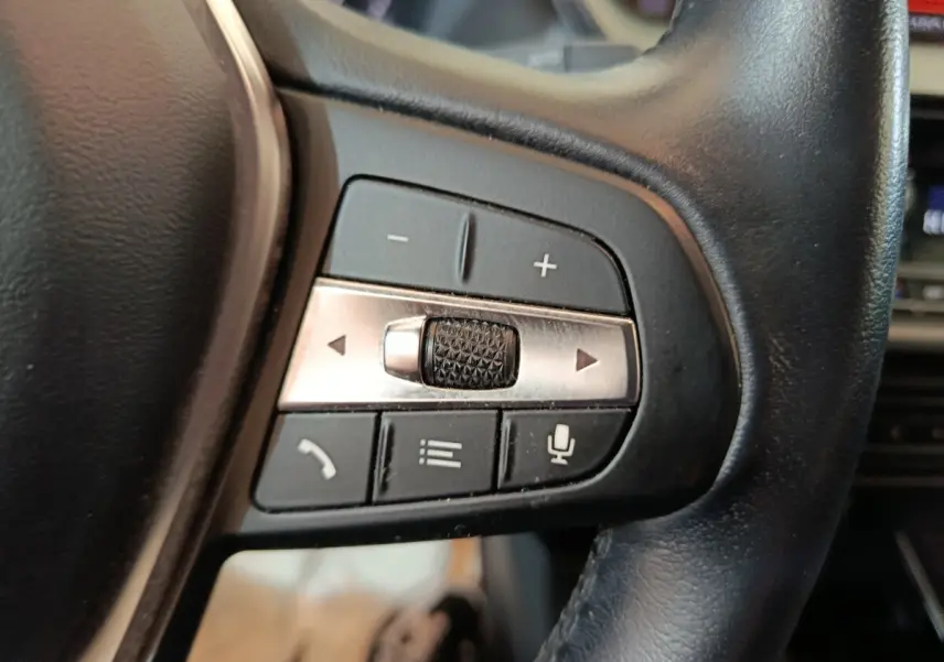 Gros plan sur les commandes multifonctions du volant en cuir noir de la BMW Série 1 118i Edition Sport 2023.