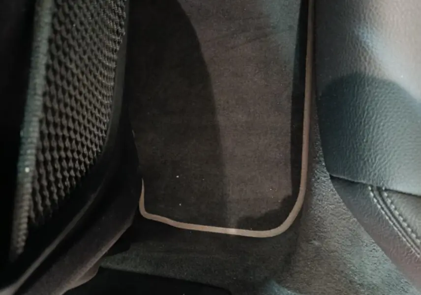 Vue rapprochée du tapis de sol noir avec surpiqûres claires côté passager arrière d'une BMW Série 1 118i Edition Sport 2023.