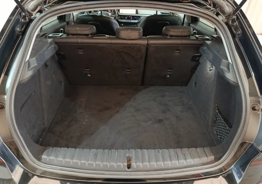 Coffre ouvert vu de l'arrière d'une BMW Série 1 118i Edition Sport noire, montrant l'espace de chargement et la banquette arrière.
