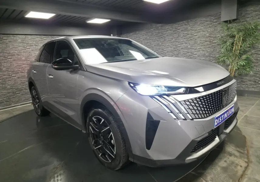 Peugeot 3008 gris métallisé en 3/4 avant droit, avec calandre noire laquée et feux LED allumés.