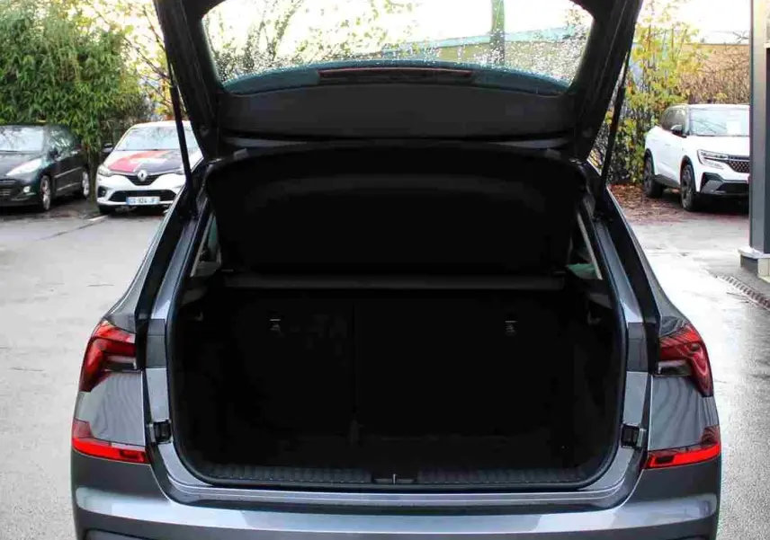 Vue arrière d'un Skoda Kamiq gris graphite 2025 avec coffre ouvert, mettant en valeur ses feux LED et son hayon spacieux.