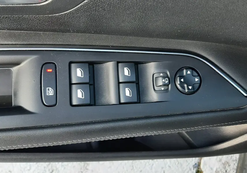 Gros plan sur les commandes de lève-vitres et réglages des rétroviseurs côté conducteur d'un Peugeot 3008 gris Amazonite.