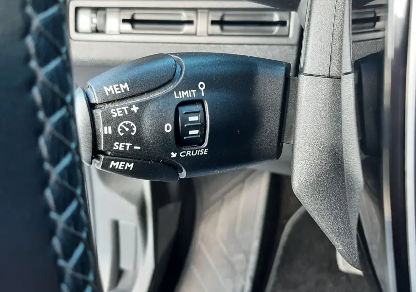 Gros plan sur la commande de régulateur de vitesse noire dans l'habitacle du Peugeot 3008 gris Amazonite.