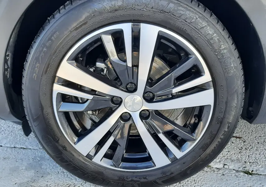 Gros plan sur la jante alliage bicolore noir et argent d’un Peugeot 3008 gris Amazonite, vue côté droit.