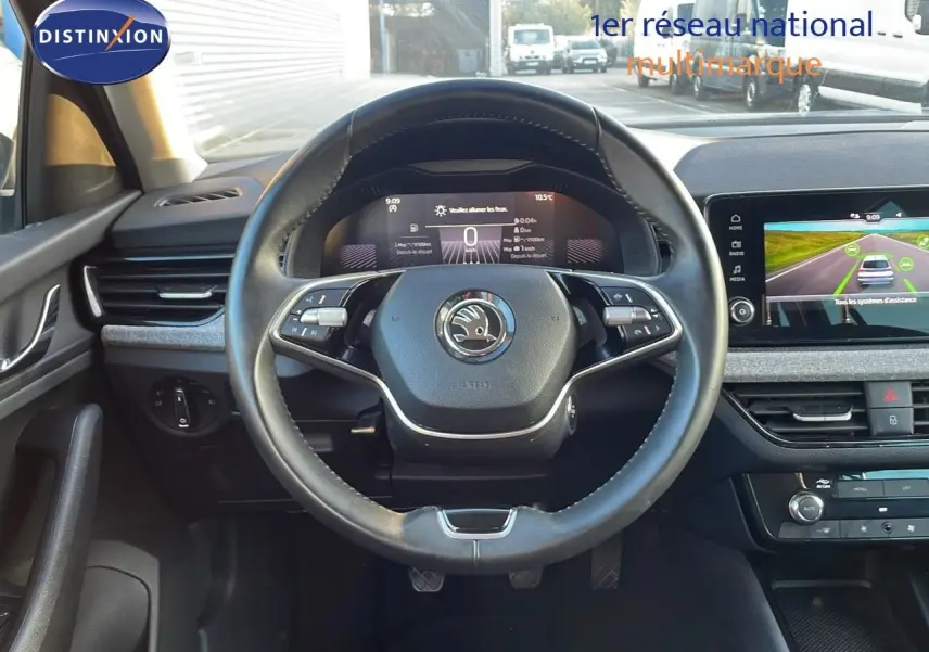 Vue intérieure centrée sur le volant cuir du Skoda Kamiq 2024, tableau de bord digital et écran tactile visibles.