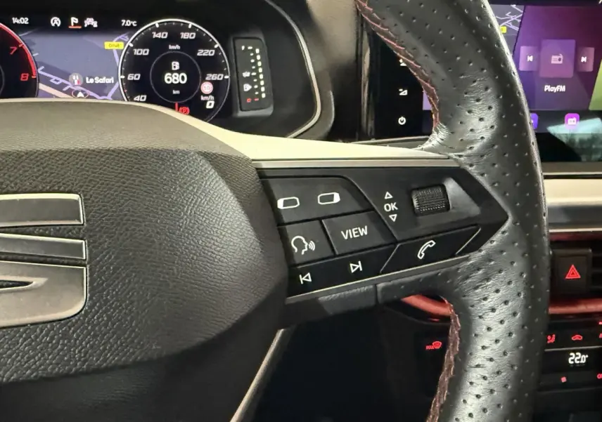 Gros plan sur le volant cuir perforé avec commandes multifonctions, tableau de bord digital et écran tactile de la SEAT Ibiza blanche 2024.