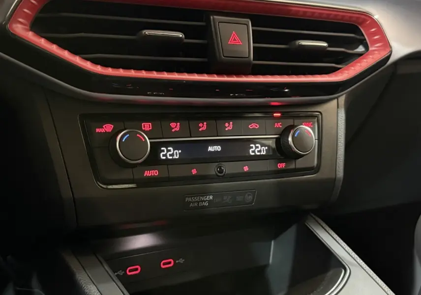 Détail de la console centrale de la SEAT Ibiza blanche 2024, avec commandes de climatisation et éclairage rouge.