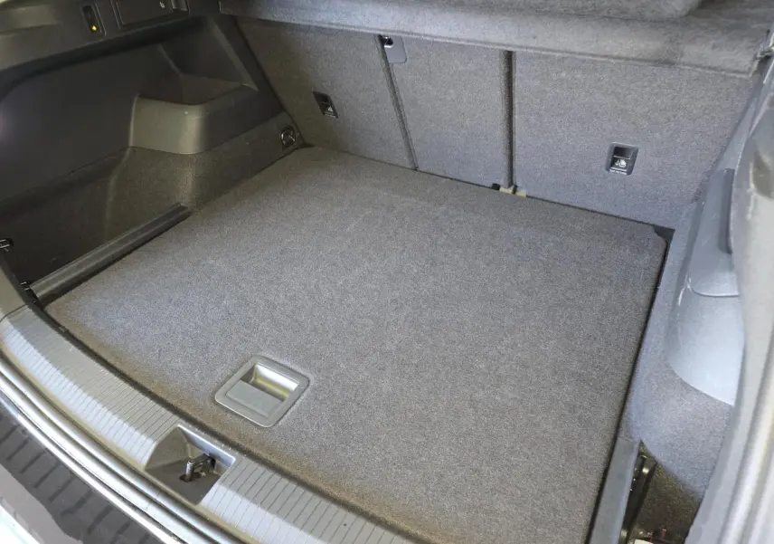 Coffre spacieux vu de dessus du Volkswagen Tiguan noir 2025 avec revêtement gris et crochet d'attelage escamotable.