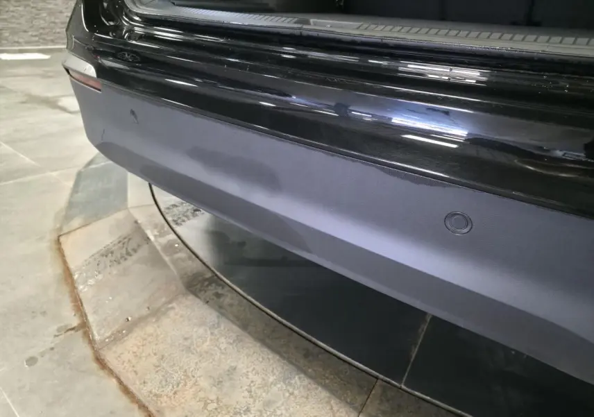 Vue rapprochée du pare-chocs arrière noir du Volkswagen Tiguan 2025 avec capteurs de stationnement intégrés.